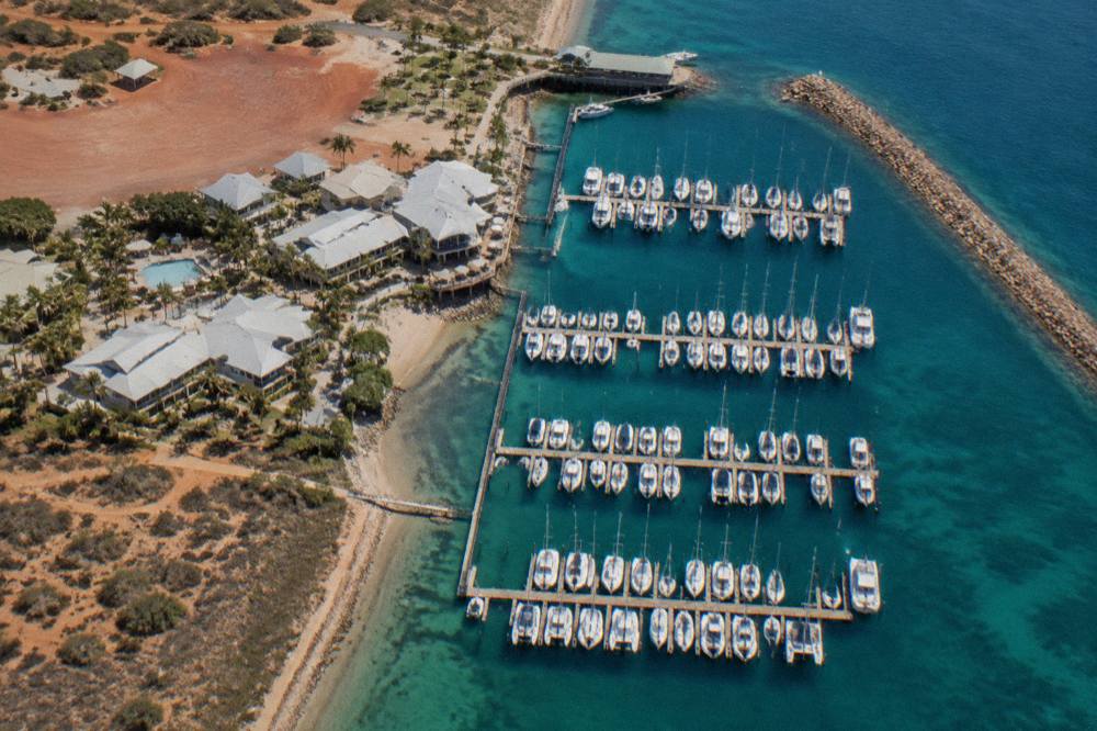 Aerial view of Exmouth Marina with boats moored along the jetty and resort buildings along the waterfront